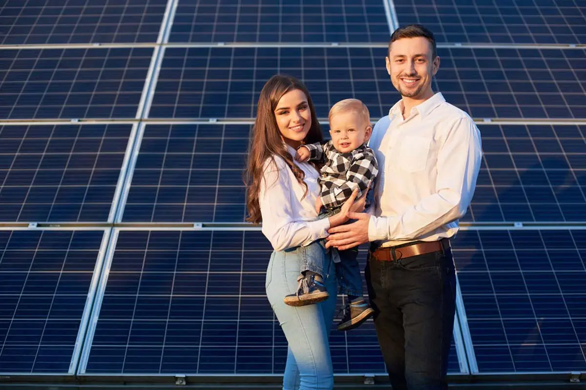 Three individuals standing in front of solar panels